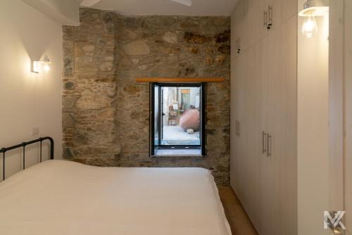 Bett in einem Zimmer mit einer Steinmauer in der Unterkunft Balkoni Moutoullas in Moutoullas