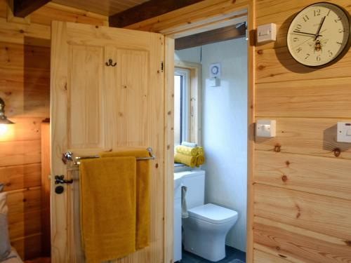 a bathroom with a clock on the wall and a toilet at Glenkens Lodge in Dalry