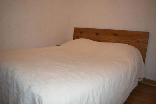 a white bed with a wooden headboard in a bedroom at Saint lary soulan village T2 Avec parking in Saint-Lary-Soulan