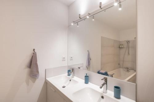 La salle de bains blanche est pourvue d'un lavabo et d'un miroir. dans l'établissement Cabana & L' Horeb - Hypercentre, à Paray-le-Monial