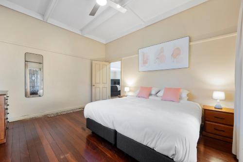 a bedroom with a large white bed with pink pillows at Swainson on Coombe in Woodville