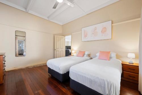 two beds in a room with white walls and wood floors at Swainson on Coombe in Woodville