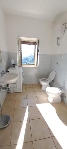 baño con lavabo y aseo y ventana en casa con 2 camere in borgo medievale, en Montegiovi