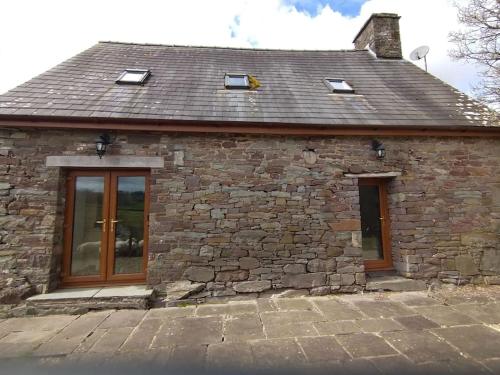 a stone house with glass doors and a roof at Wern Ddu, Defynnog - Brecon Beacons in Brecon