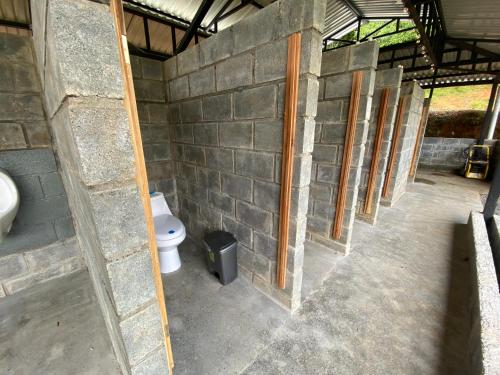 uma casa de banho com um WC numa parede de tijolos em Esquipulas Rainforest em Quepos