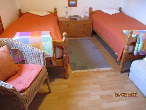 een slaapkamer met 2 bedden, een stoel en een dressoir bij Haus mit Lilie und Rose in Westerdeichstrich