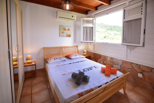 una camera con un letto in una stanza con una finestra di Villa Sohalia climatisée, piscine et jardin à 5mn de la plage a Le Diamant