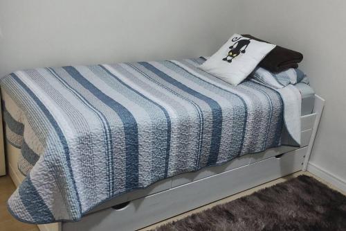Una cama con una manta de rayas azul y blanca. en Apartamento Lindo e Confortável com 2 quartos e estacionamento grátis Curitiba, en Curitiba
