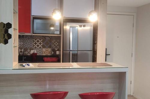 una cocina con dos taburetes rojos frente a un mostrador en Apartamento Lindo e Confortável com 2 quartos e estacionamento grátis Curitiba, en Curitiba