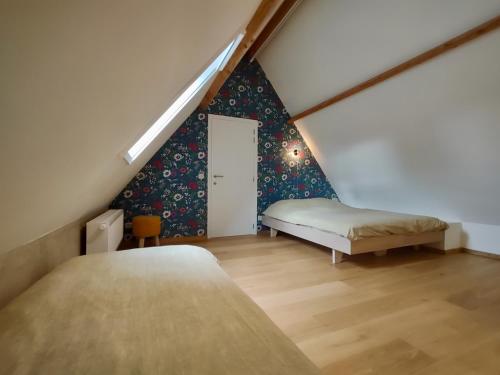 a attic bedroom with a bed and a staircase at Nachtegael Zomerhuis, idyllische woning in de Vlaamse Ardennen in Kluisbergen
