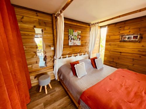een slaapkamer met een bed in een kamer met houten wanden bij Gîte Paradis Lé La in L'Étang-Salé