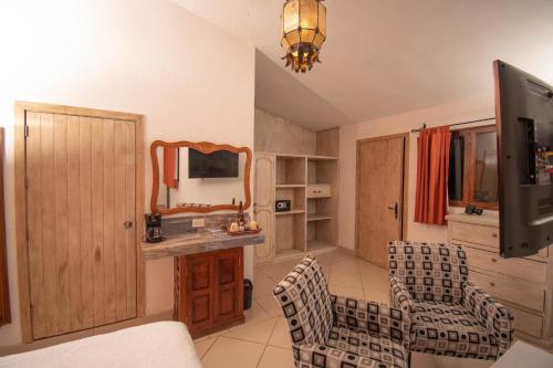 a living room with a tv and chairs and a mirror at Casa María Elena in San Miguel de Allende