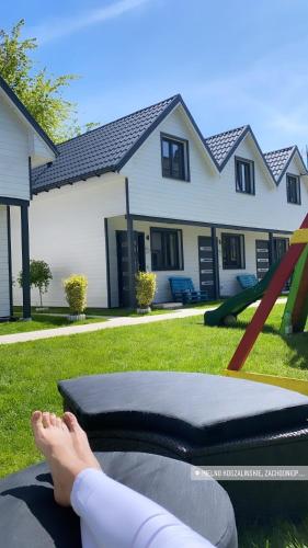 a woman laying on a bed in a yard with her feet on it at Tu Urlop in Mielno