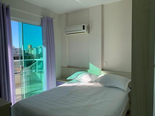 1 dormitorio con cama y ventana con vistas en Residencial Açores, en Bombinhas
