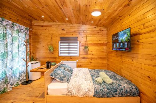 a bedroom with a bed in a wooden cabin at Au coucher du soleil, chalet avec jacuzzi et sauna in Vieux-CondÃ©