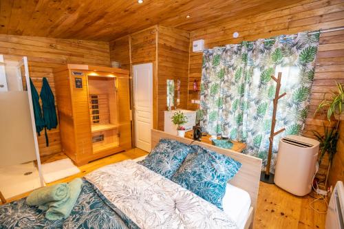 una camera con un letto in una stanza con pareti in legno di Au coucher du soleil, chalet avec jacuzzi et sauna a Vieux-CondÃ©