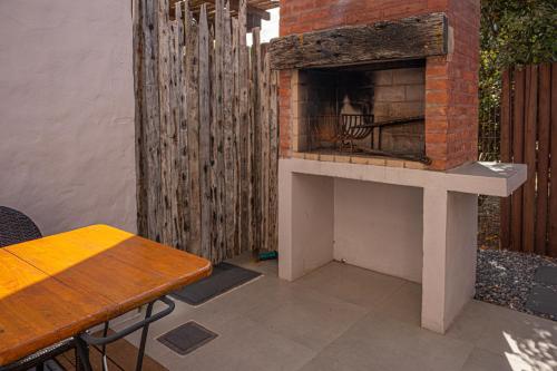 a patio with a brick fireplace next to a wooden fence at Muelles del Diablo Tranquilo in Punta Del Diablo