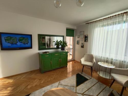 ein Wohnzimmer mit einem grünen Schrank und einem Stuhl in der Unterkunft Relax Apartment Suwałki in Suwałki