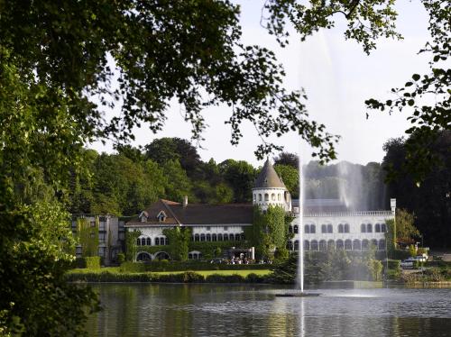 un bâtiment avec une fontaine au milieu d'un lac dans l'établissement Martin's Château Du Lac, à Genval