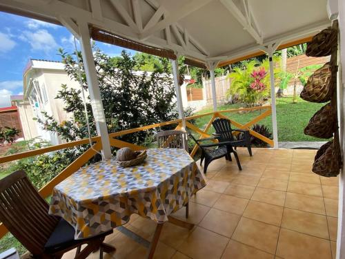 un patio con mesa y sillas en un porche en Charmant bungalow avec piscine Kaz' Basse, en Bouillante