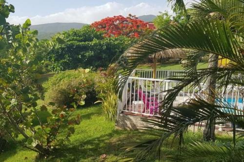 a garden with a white fence and a pool at Charmant bungalow avec piscine Kaz' Basse in Bouillante
