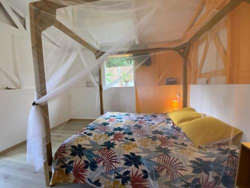 a bedroom with a canopy bed in a room at Charmant bungalow avec piscine Kaz' Basse in Bouillante