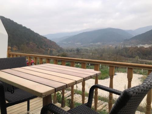 a wooden table and chairs on a balcony with mountains at DENGEKORU Wildlife & Glamping in Mudurnu