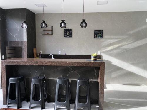 a kitchen with a counter with black stools at Casa de Praia Lado Sul in Guriri