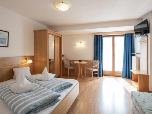 a hotel room with two beds and a table at Hotel B&B Martha in Brunico