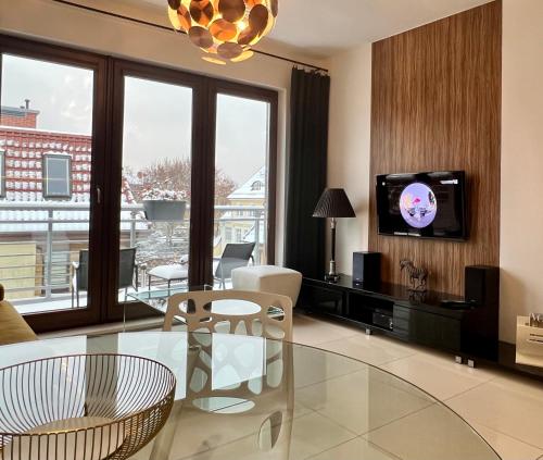 a living room with a glass table and a tv at Sopocka Bryza in Sopot