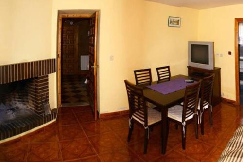 a dining room with a table and chairs and a fireplace at Casa rural Huertos de Sayago in Moralina