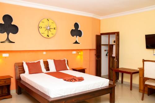 1 dormitorio con 1 cama y reloj en la pared en Amazone Hotel Tulear en Toliara