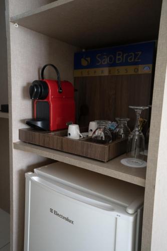 a kitchen with a refrigerator and a red suitcase on a shelf at Hotel Cabo Branco Atlântico in João Pessoa