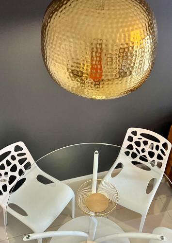 a glass table with two chairs and a lamp at Sopocka Bryza in Sopot