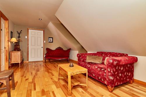 a living room with a red couch and a table at Auberge de la Tour et Spa in Magog-Orford