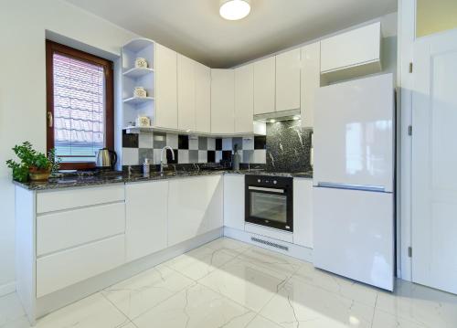 a white kitchen with white cabinets and appliances at Studio Gdańsk - Oliwa in Gdańsk
