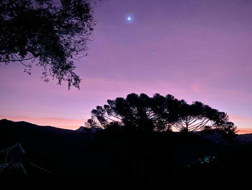 a sunset with a tree and the moon in the sky at Atiaia Jungle River Retreat in Visconde De Maua