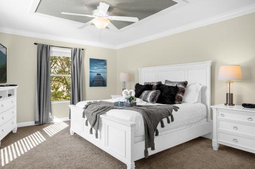 a white bedroom with a bed and a ceiling fan at Fun Family Villa Pool BBQ Near Disney World 5BR in Kissimmee