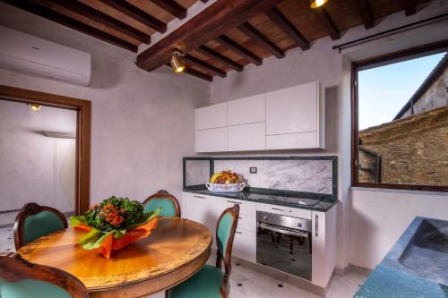 une cuisine avec une table et des chaises en bois, une table et une cuisinière dans l'établissement IBibiena - SUITE DEL CARDINALE, à Bibbiena