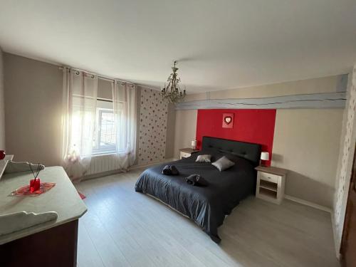 a bedroom with a black bed and a red wall at Gîte le Calyaden in Athis