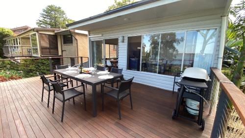 eine Terrasse mit einem Tisch und Stühlen auf einer Terrasse in der Unterkunft Absolute lakefront house - enjoy the sunrise in Budgewoi