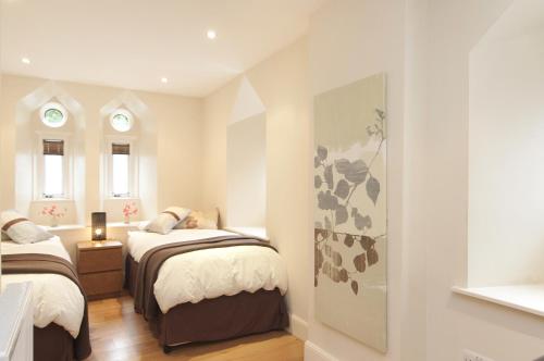 a small bedroom with two beds and two windows at Edinburgh Church Apartments in Edinburgh