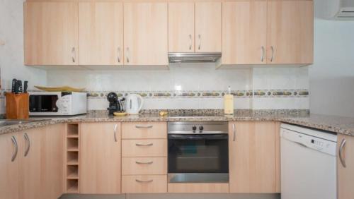 a kitchen with wooden cabinets and white appliances at Casa Port Grec in Empuriabrava