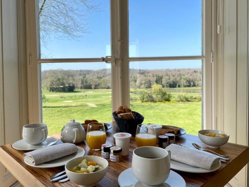 - une table avec des aliments pour le petit-déjeuner et une fenêtre avec vue dans l'établissement Hôtel de Boisgelin, à Pléhédel