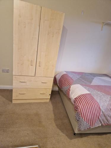 a bedroom with a bed and a wooden dresser at Chique Maidstone Studio III in Kent