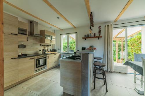 uma cozinha com armários de madeira e um bar com bancos em Belle maison rénovée, 5mn à pied de la mer, classée meublé de tourisme 3 étoiles em Île-Tudy