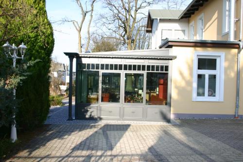 a building with a conservatory on the side of a house at Hotel Sonneneck in Zinnowitz