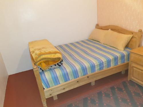 a small bed in a corner of a room at Guest House Imdoukal in Aït Tamellil