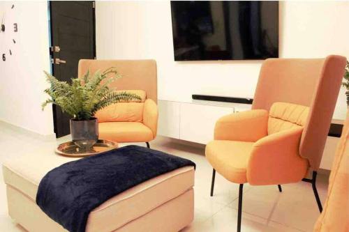 a living room with two chairs and a ottoman at Las Cayenas Residéncial in Santo Domingo