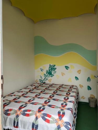 a bedroom with a bed with a colorful bedspread at Aluguel de mini quartos e barracas no Perequê-açu de frente para o mar numero 1125 in Ubatuba